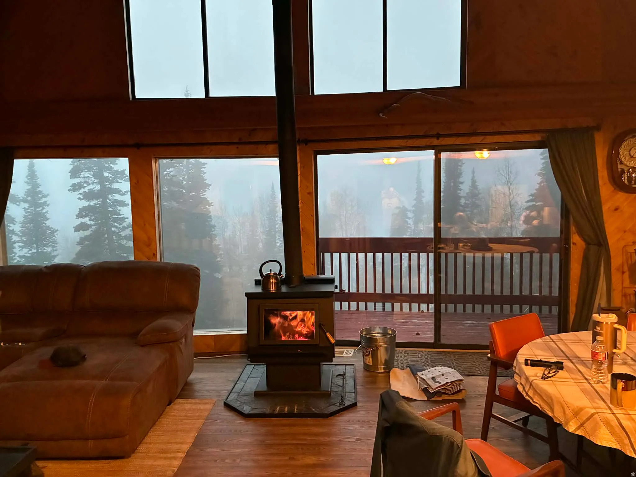 Living room featuring a wood stove, wood walls, wood finished floors, and a high ceiling