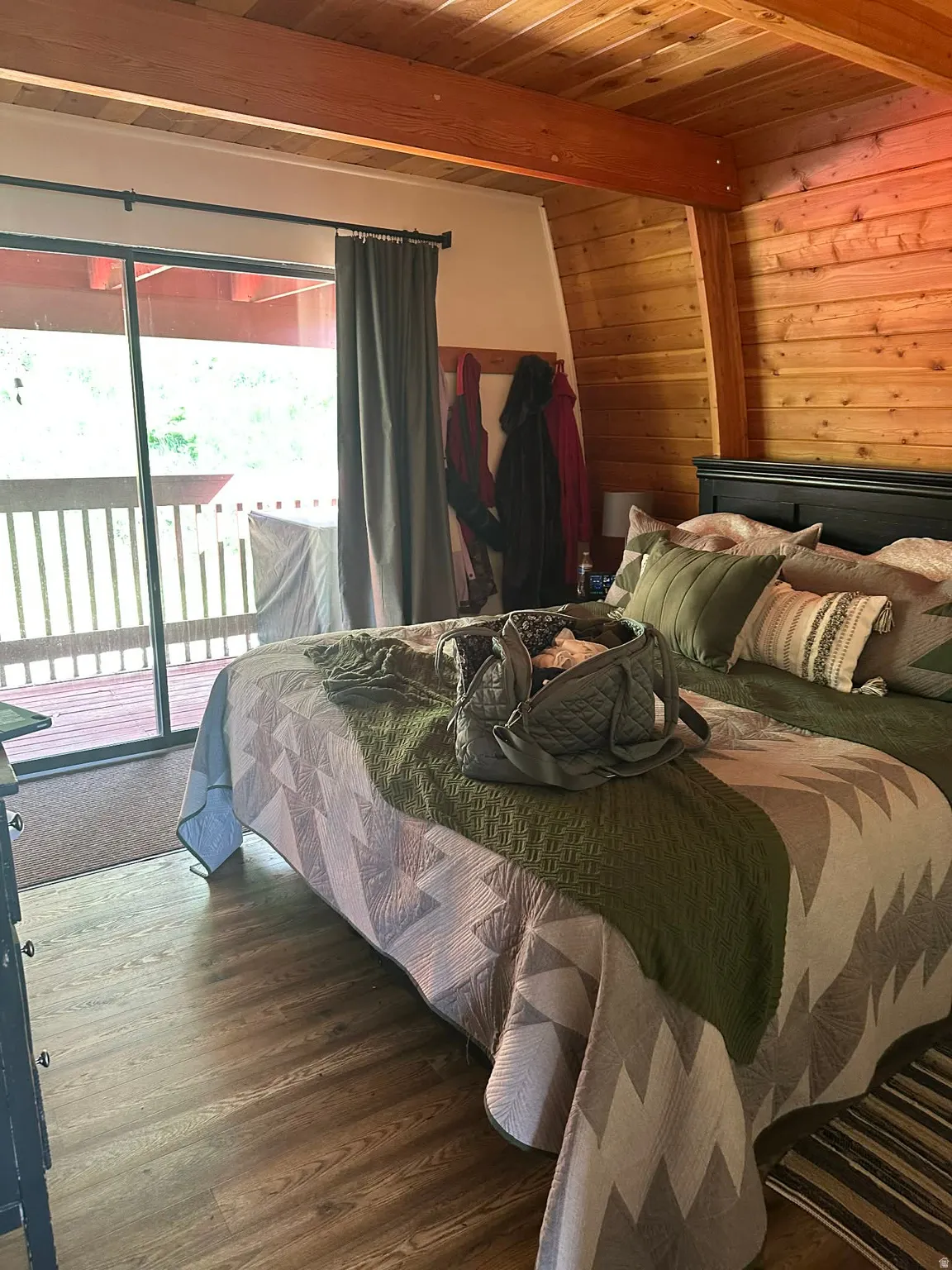Bedroom with access to outside, wood finished floors, wooden walls, and a wood ceiling with exposed beams