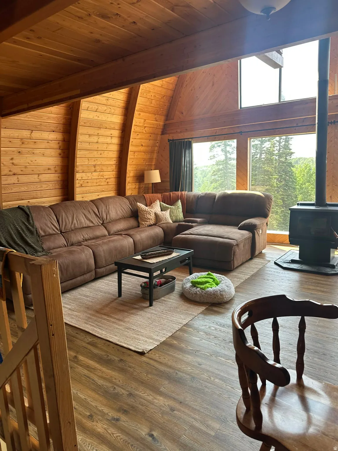 Living room featuring a wood stove, wood walls, wood ceiling, and hardwood / wood-style floors