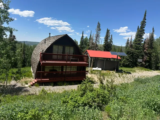 Back of property with solar panels, a deck, and an outdoor structure