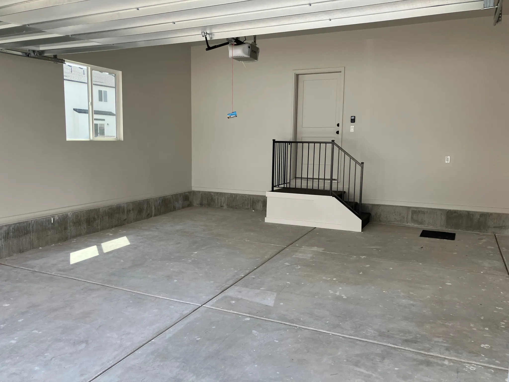 Spacious garage featuring concrete flooring, an interior access door with black handrail, and a window