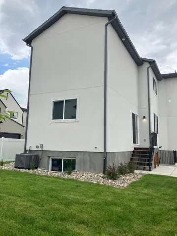 Contemporary stucco exterior with dark gray trim and gutters