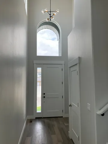 Two-story entry featuring an arched window and a contemporary chandelier