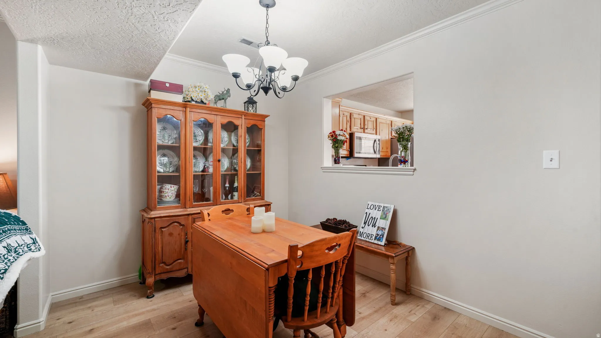 Office space featuring a chandelier, light wood-style floors, a textured ceiling, and crown molding