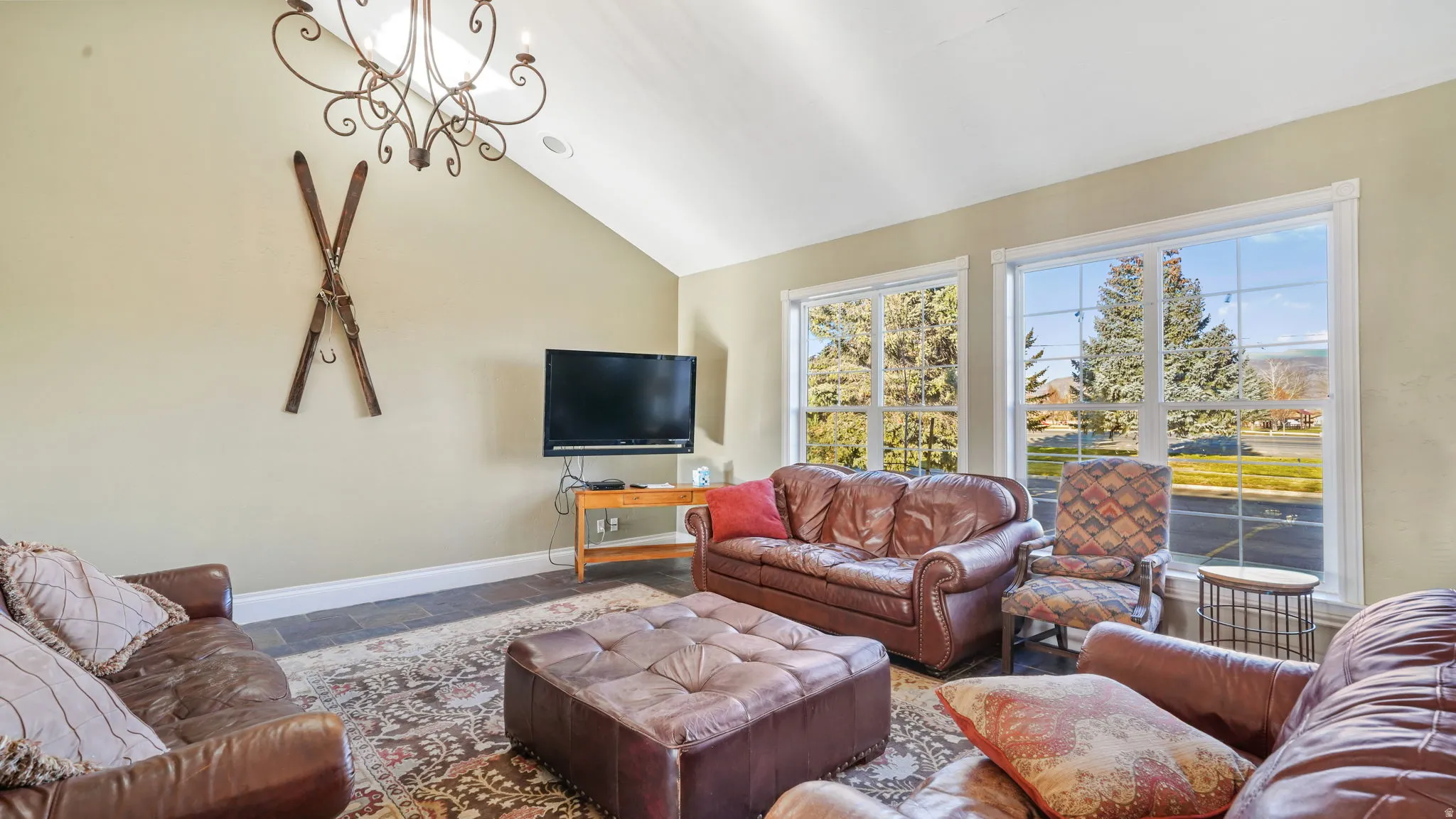 Living room featuring stone tile flooring, lofted ceiling, and a chandelier