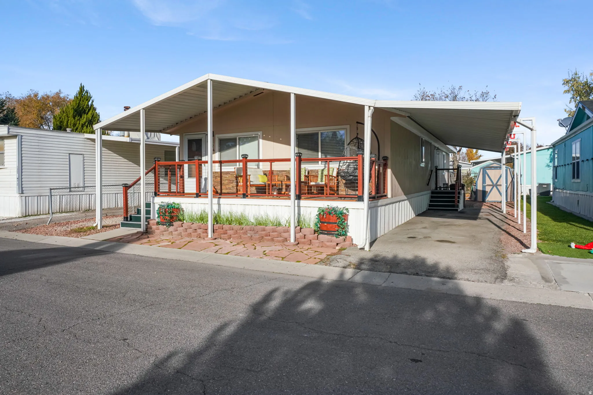 Manufactured / mobile home featuring an attached carport, a porch, and an outbuilding