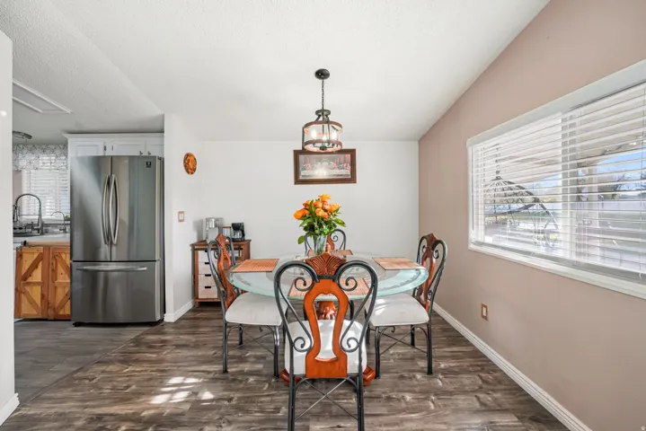 Dining room featuring healthy amount of natural light, a textured ceiling, dark wood-style flooring, and a chandelier