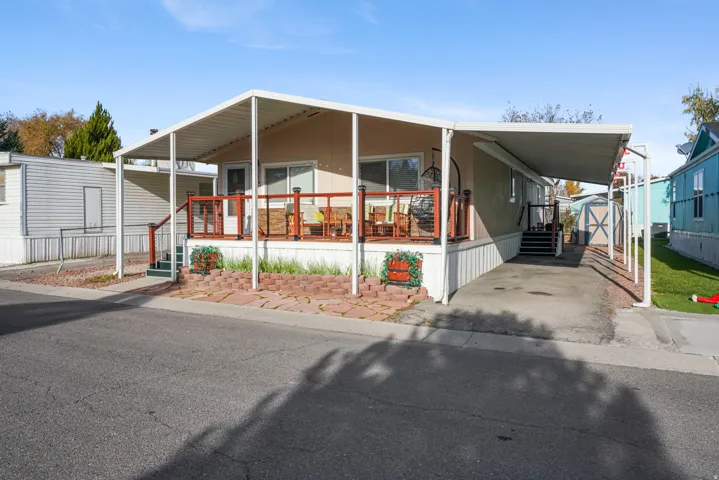 Manufactured / mobile home featuring an attached carport, a porch, and an outbuilding