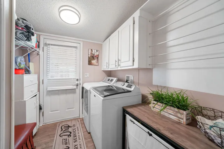 Washroom featuring a textured ceiling, cabinet space, light wood-style flooring, and washer and dryer
