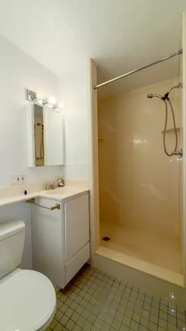 Bathroom featuring a shower stall, vanity, and light tile patterned flooring