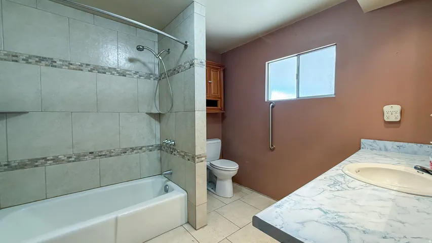 Bathroom with vanity, bathing tub / shower combination, and light tile patterned floors