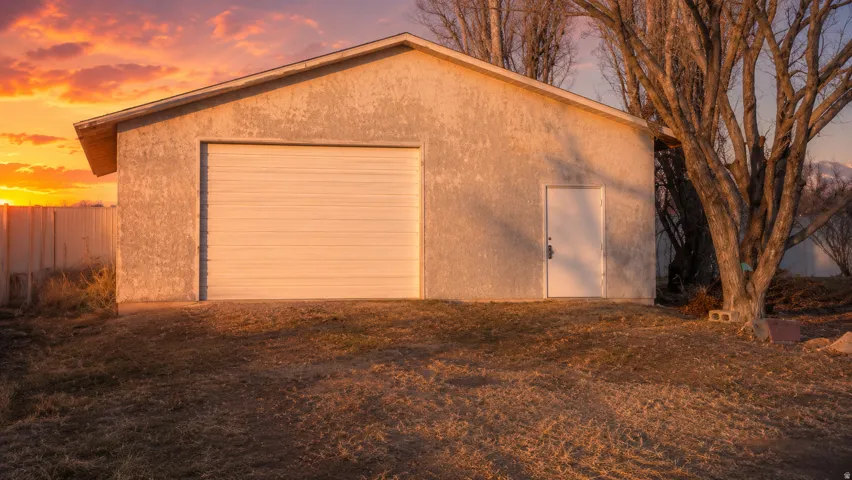Detached structure featuring a single garage door, a side entry door, and stucco exterior