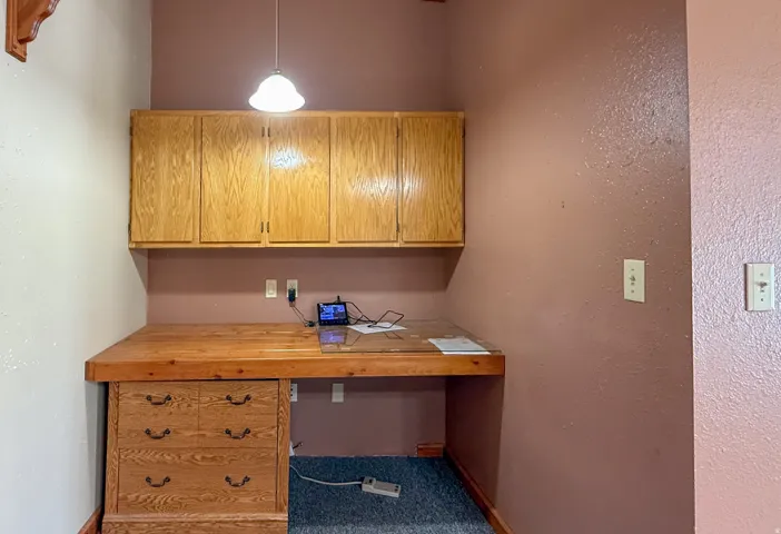Carpeted home office featuring built in desk and a textured wall