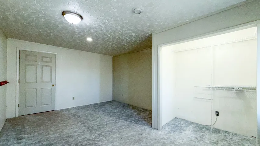 Unfurnished bedroom featuring a closet, carpet, and a textured ceiling