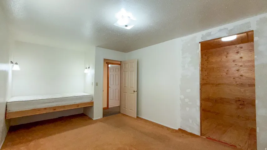 Unfurnished bedroom featuring a textured ceiling and carpet
