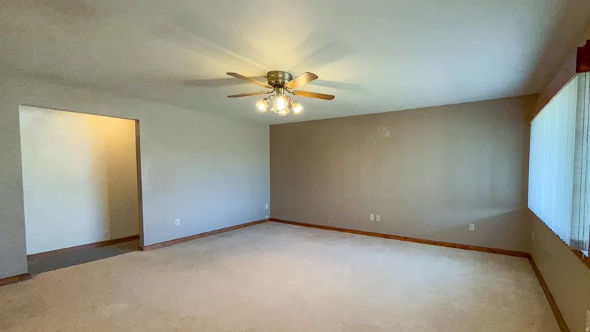 Spare room featuring light carpet and a ceiling fan