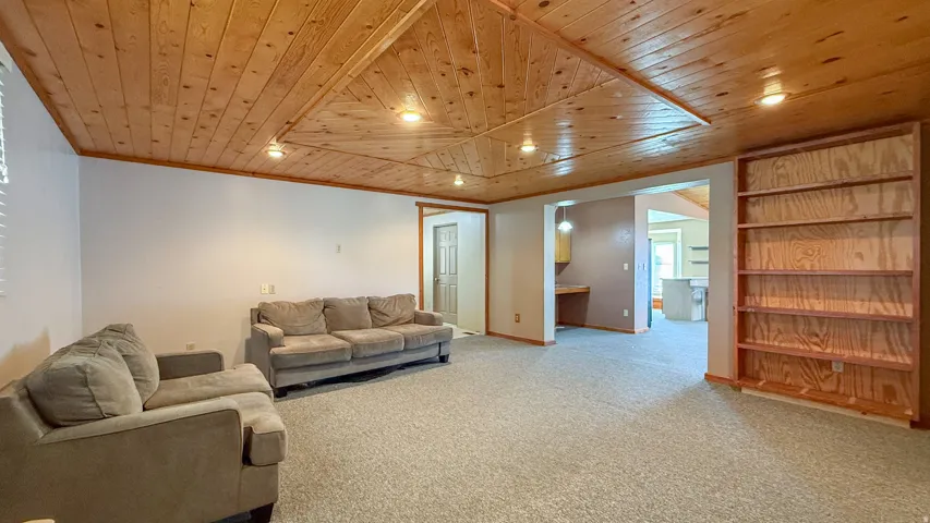 Carpeted living area featuring wood ceiling