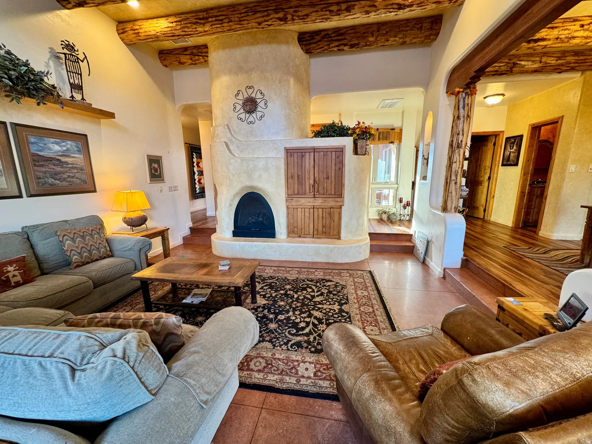 Tiled living area with beamed ceiling, a fireplace, and arched walkways