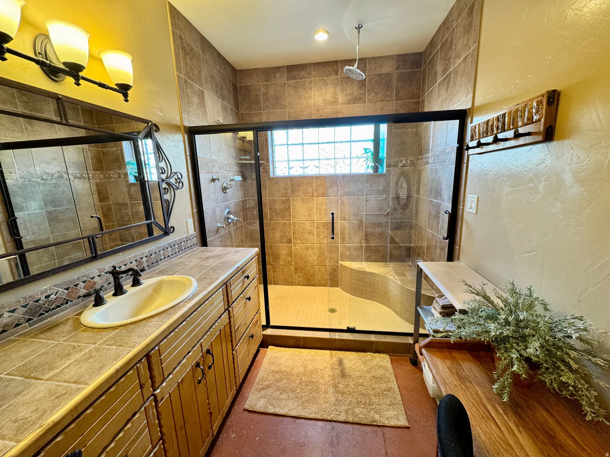 Full bath with vanity, a textured wall, and a stall shower