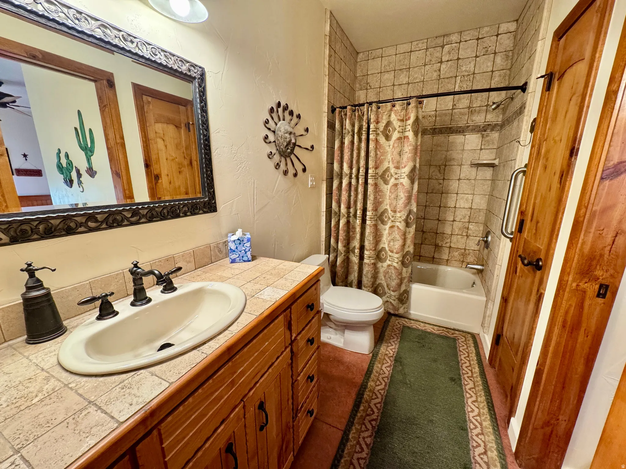 Full bath featuring vanity, a textured wall, shower / bath combo with shower curtain, and dark tile patterned floors