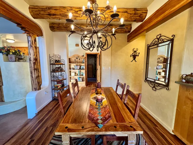 Dining area featuring beam ceiling, dark wood-style floors, and a chandelier