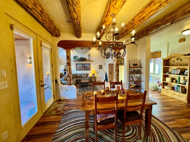 Dining area featuring beam ceiling, a chandelier, and wood finished floors