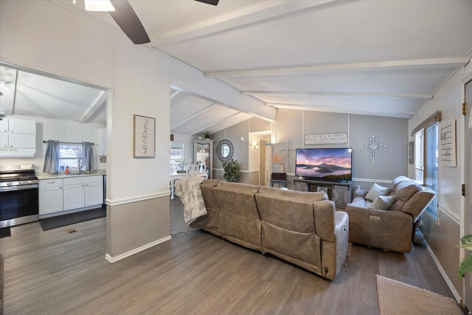 Living area with dark wood-type flooring, plenty of natural light, and a ceiling fan