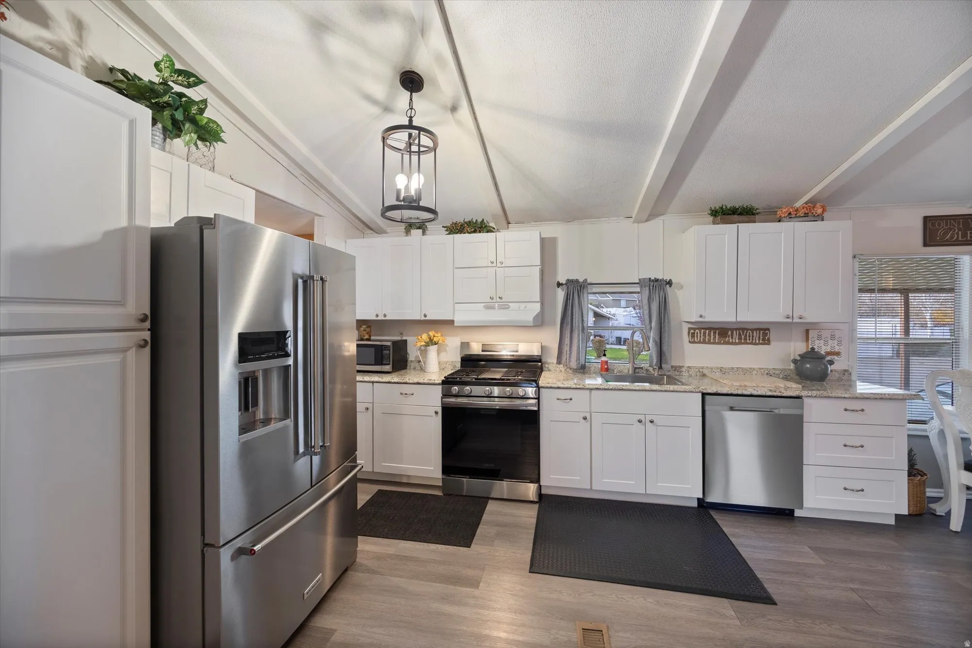 Kitchen featuring stainless steel appliances, white cabinets, pendant lighting, and dark wood finished floors