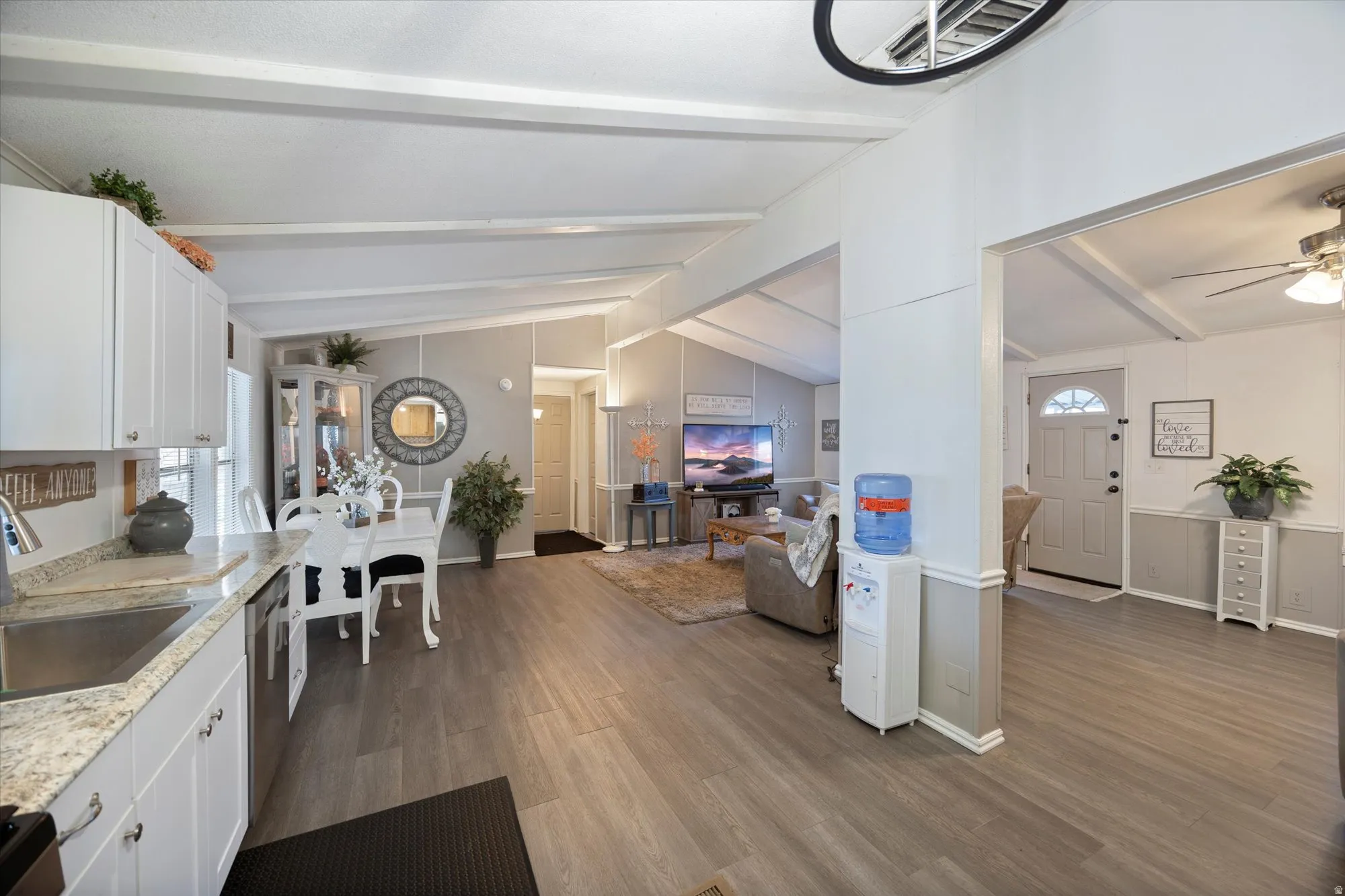 Kitchen featuring white cabinetry, dark wood-style flooring, dishwasher, open floor plan, and ceiling fan