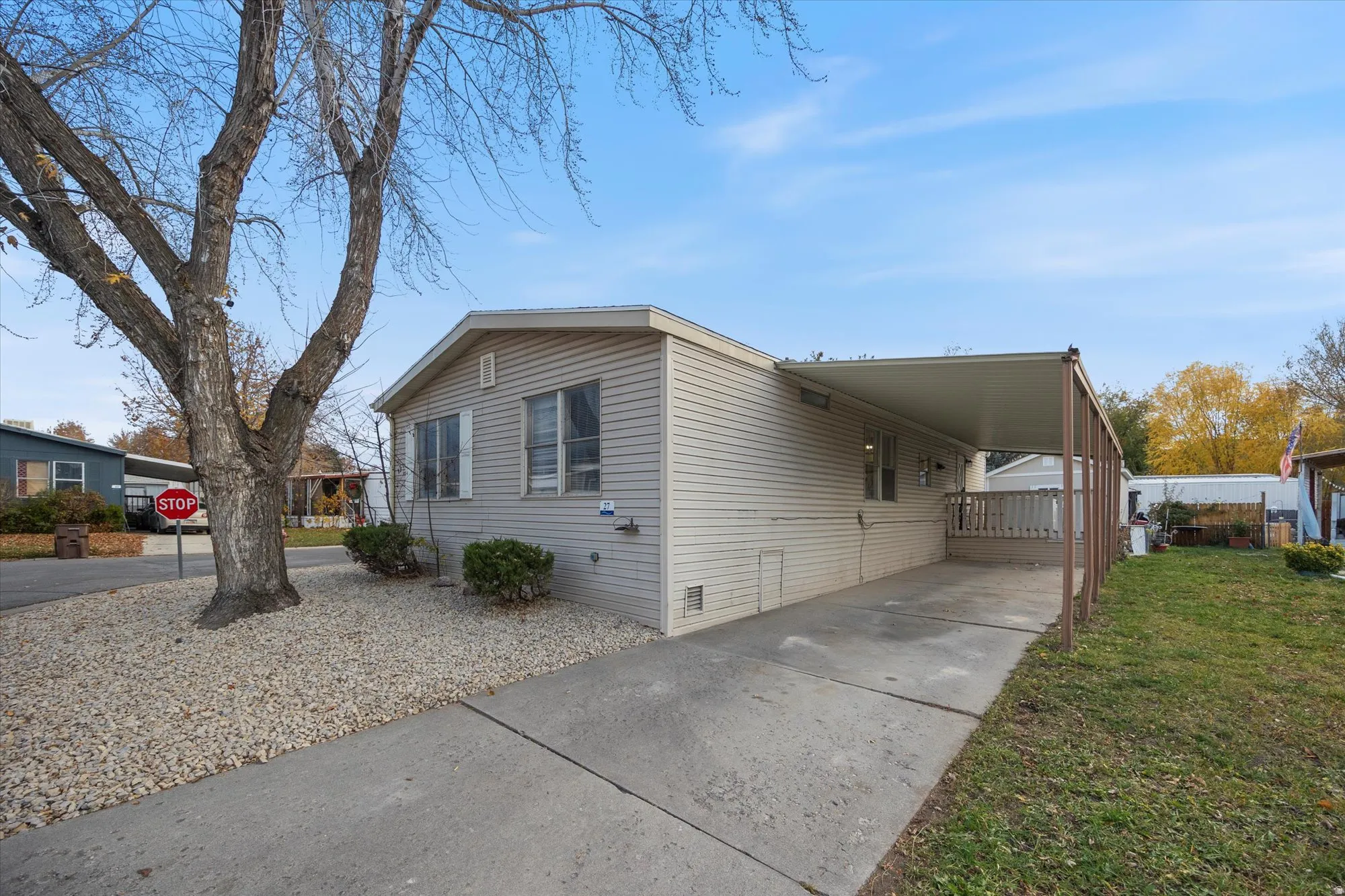 View of front facade with an attached carport, concrete driveway, and a front yard