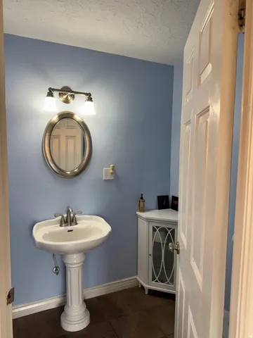 Bathroom with dark tile patterned floors and a textured ceiling
