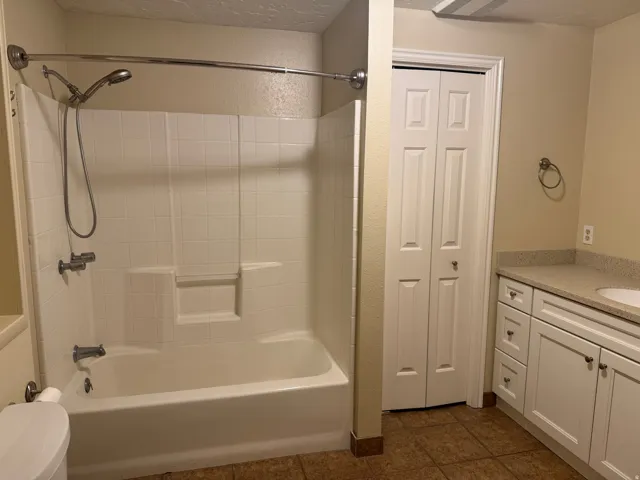 Bathroom featuring vanity, a closet, bathing tub / shower combination, dark tile patterned floors, and a textured ceiling