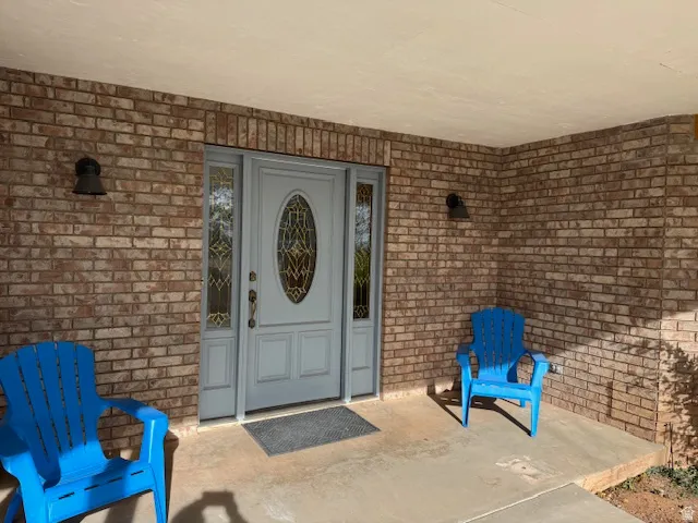 View of exterior entry with brick siding and a patio area