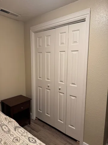 Storage room featuring dark wood-type flooring, a closet, a textured wall, and a textured ceiling