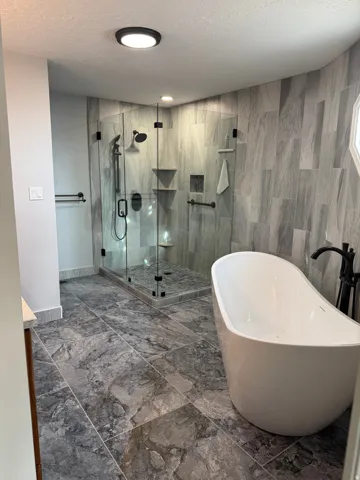 Full bath featuring a soaking tub, a textured ceiling, a shower stall, dark marble finish flooring, and vanity