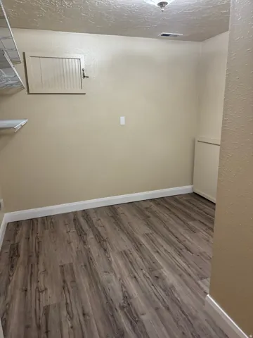 Spare room featuring a textured wall, a textured ceiling, and wood finished floors