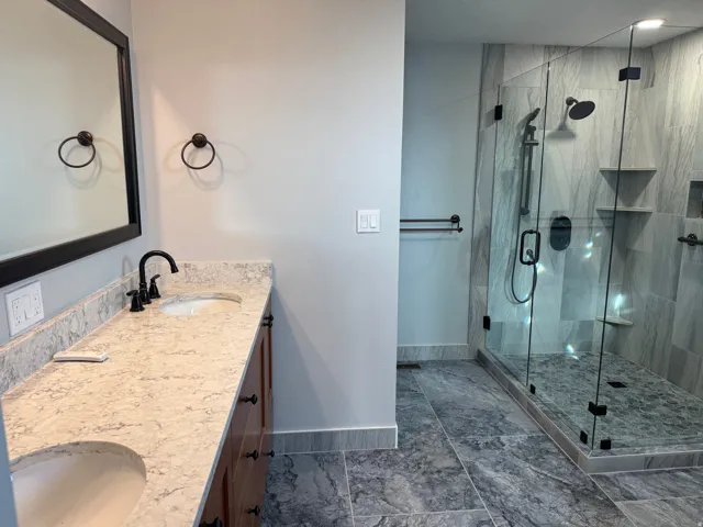 Full bath with double vanity and a stall shower