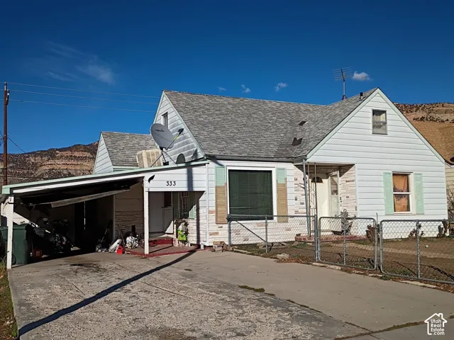 Property featuring a covered carport, concrete driveway, and a front chain-link fence