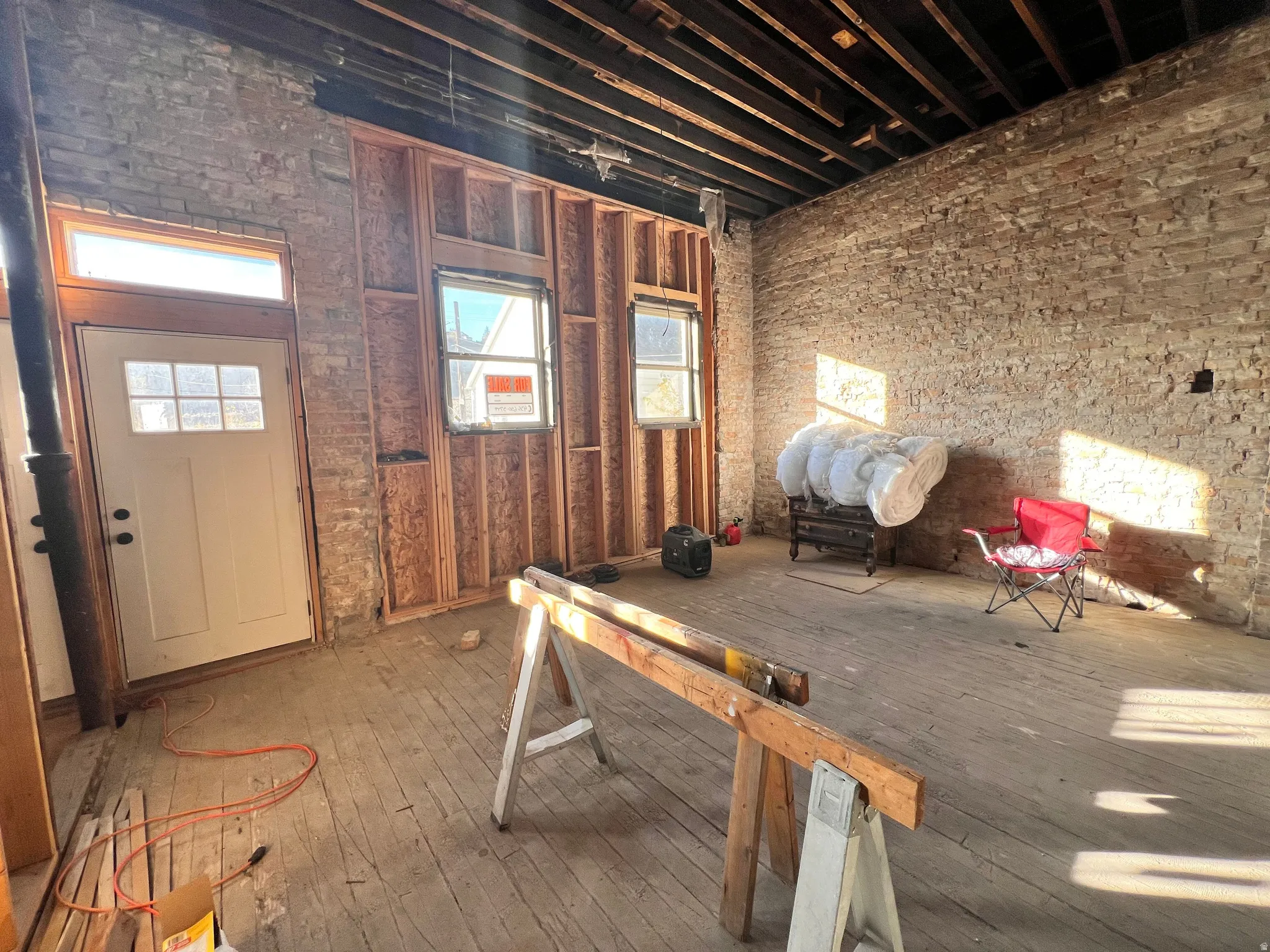 Miscellaneous room featuring brick wall and wood-type flooring