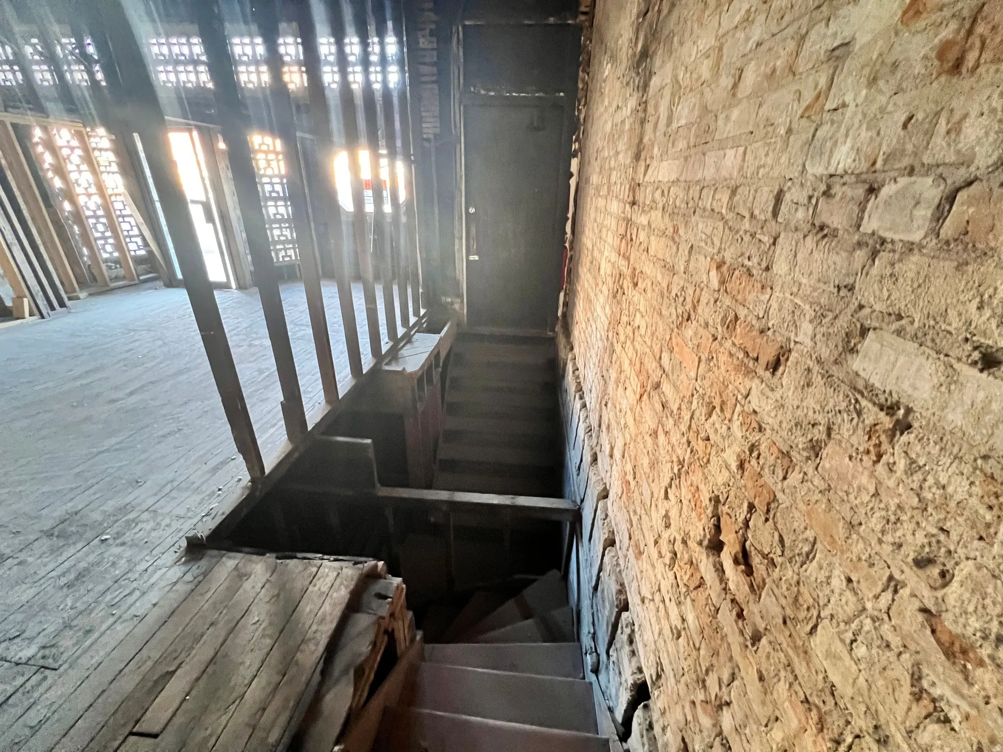 Stairway with brick wall leading to basement. Shows stairwell that is accessed by door on Main St.