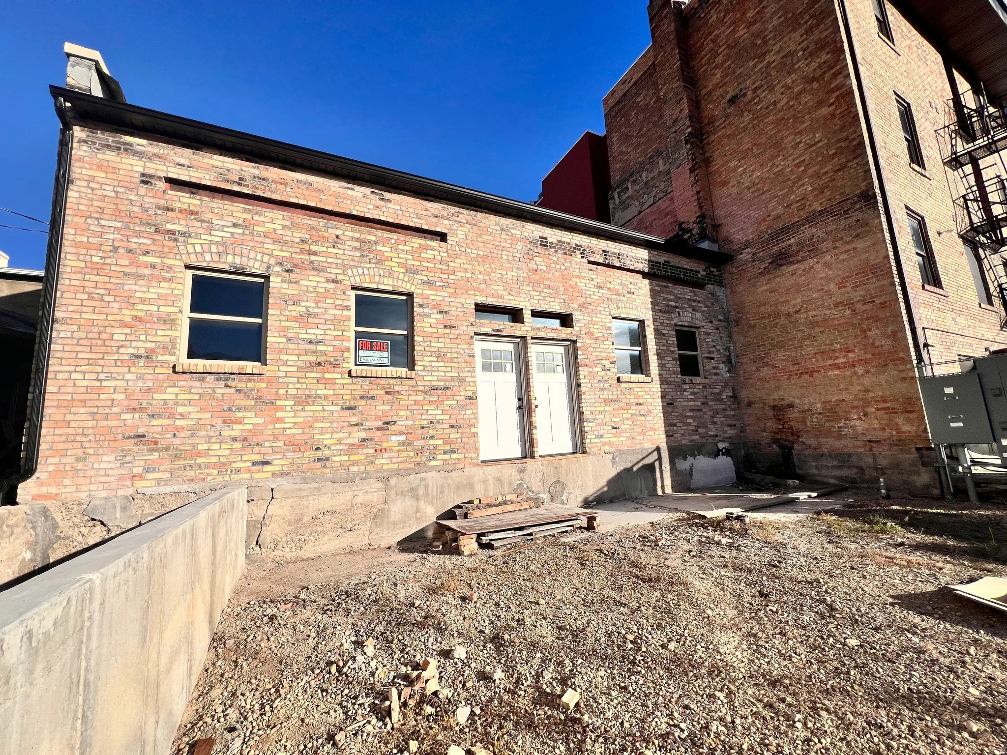 Rear view of property featuring newly laid brick siding facade and an area for a deck to be added or patio.