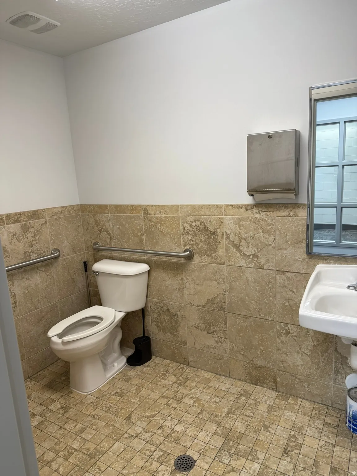 Bathroom with a wainscoted wall and tile walls