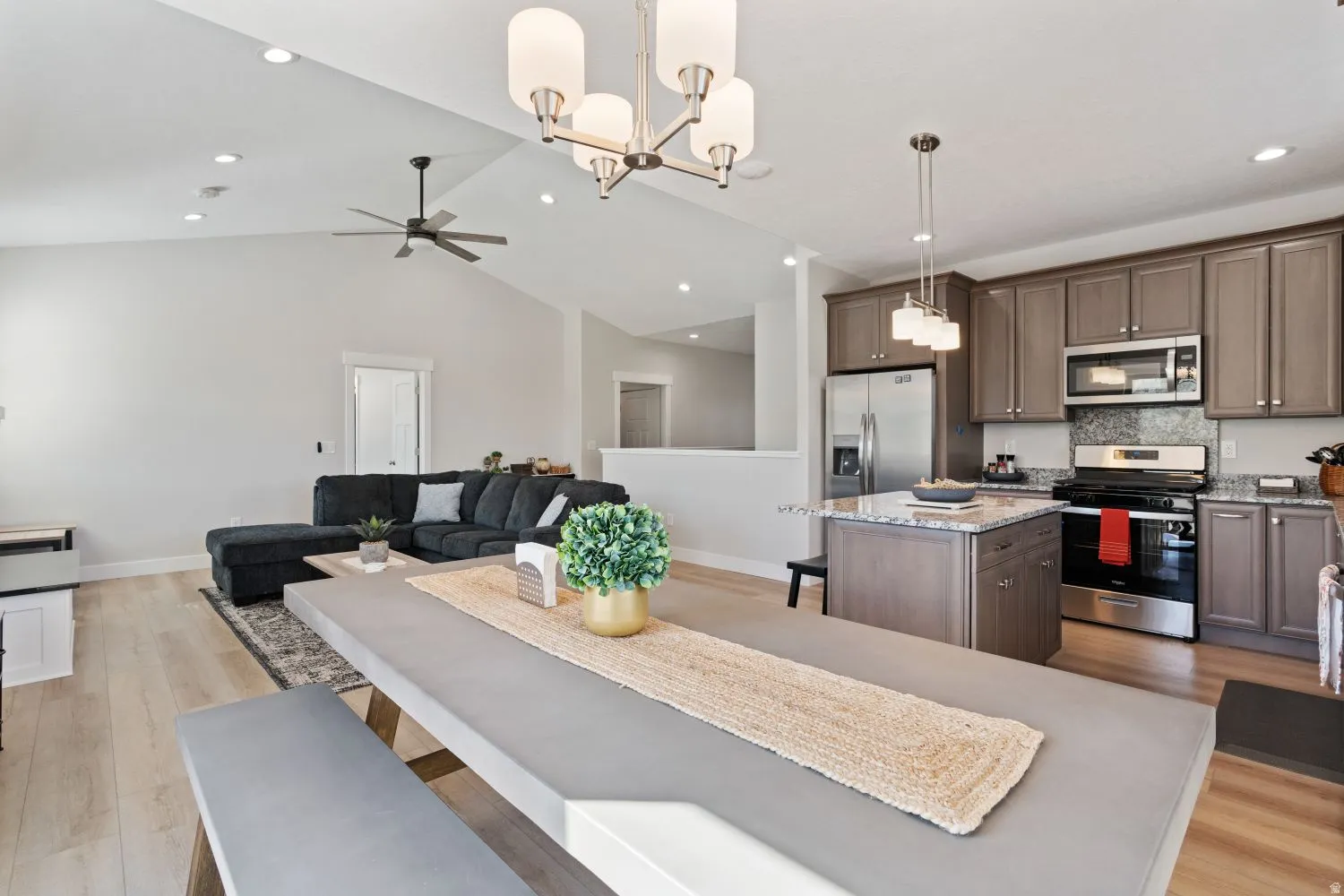 Dining space featuring light wood-style flooring, a chandelier, vaulted ceiling, recessed lighting, and a ceiling fan