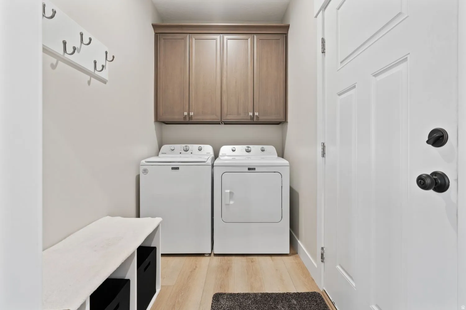 Washroom featuring separate washer and dryer, light wood-type flooring, and cabinet space