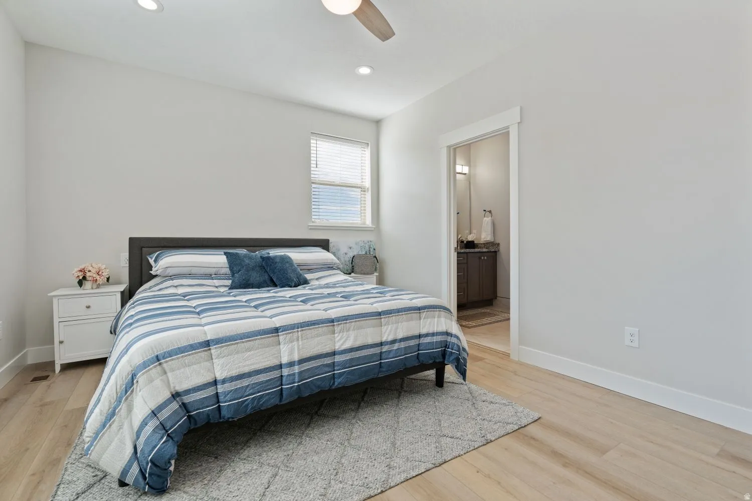 Bedroom with light wood finished floors, a ceiling fan, ensuite bathroom, and recessed lighting