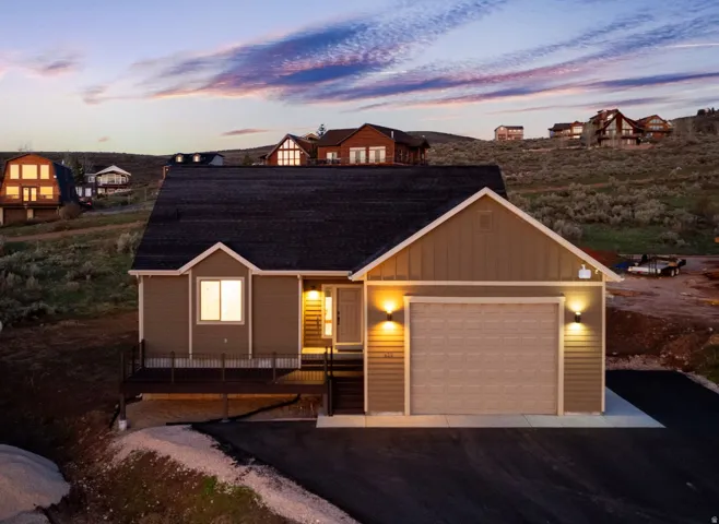 View of front facade featuring board and batten siding, an attached garage, and driveway