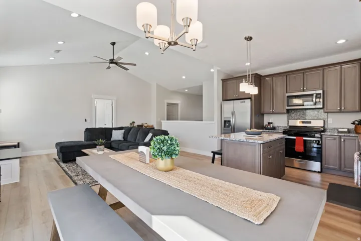 Dining space featuring light wood-style flooring, a chandelier, vaulted ceiling, recessed lighting, and a ceiling fan
