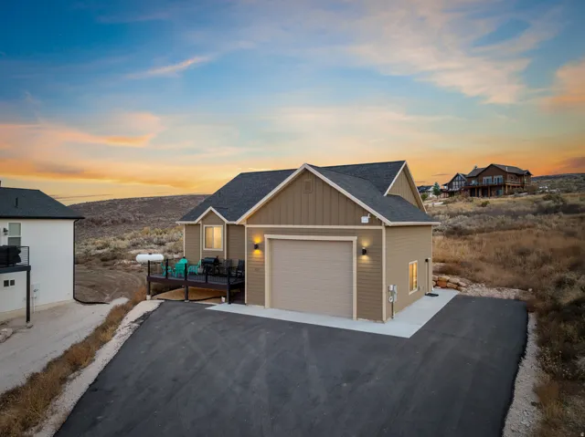 View of front of home with board and batten siding, a shingled roof, and asphalt driveway