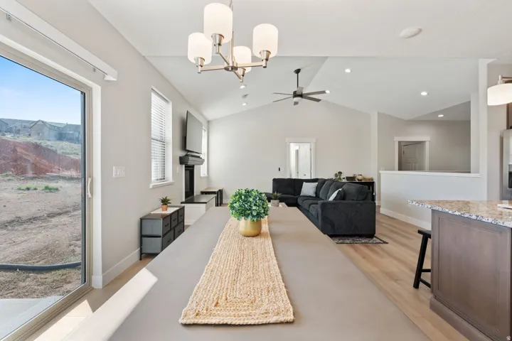 Dining room with a chandelier, lofted ceiling, light wood-style flooring, and ceiling fan
