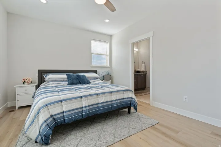 Bedroom with light wood finished floors, a ceiling fan, ensuite bathroom, and recessed lighting
